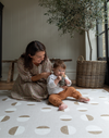 Mother and child enjoy play time in comfort on a durable play rug that has a modern look with stylised solstice motif