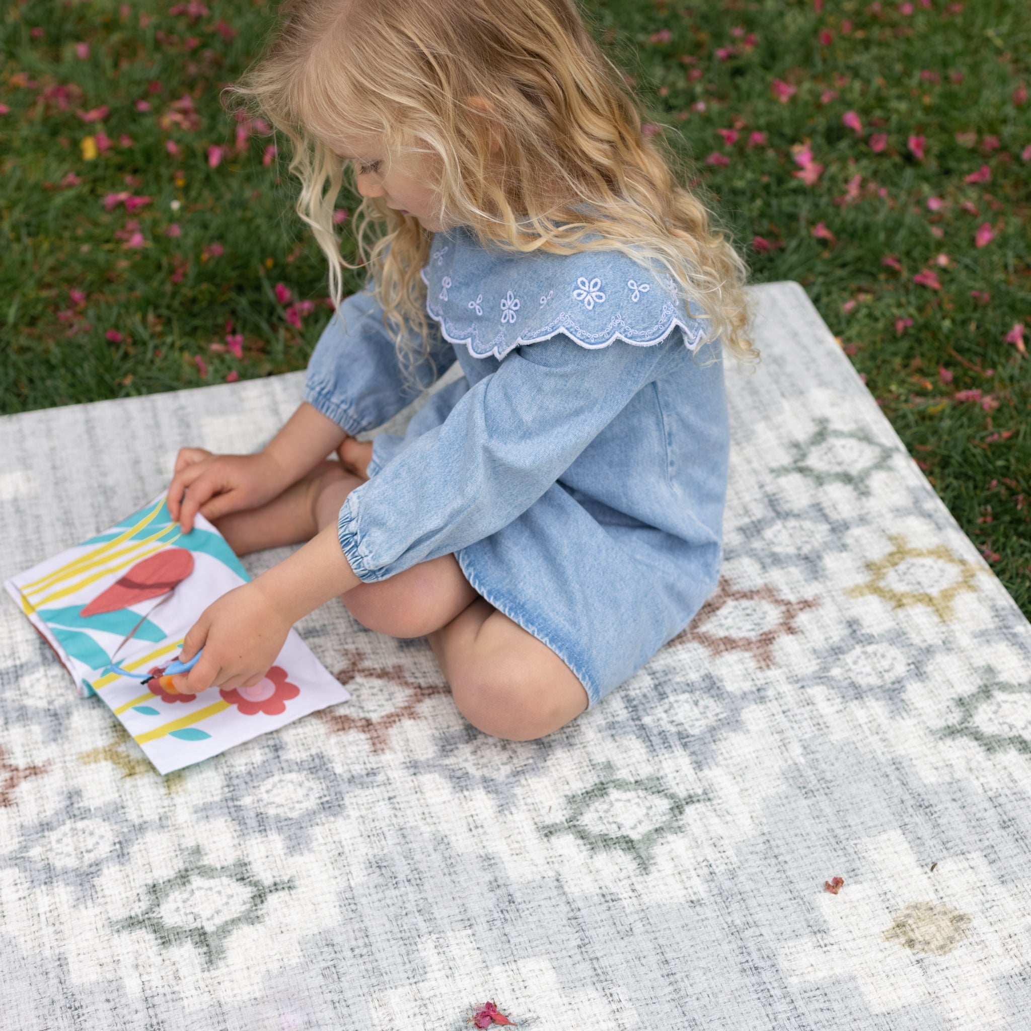 Girl sat outside playing on geometric totter and tumble memory foam safe play mat
