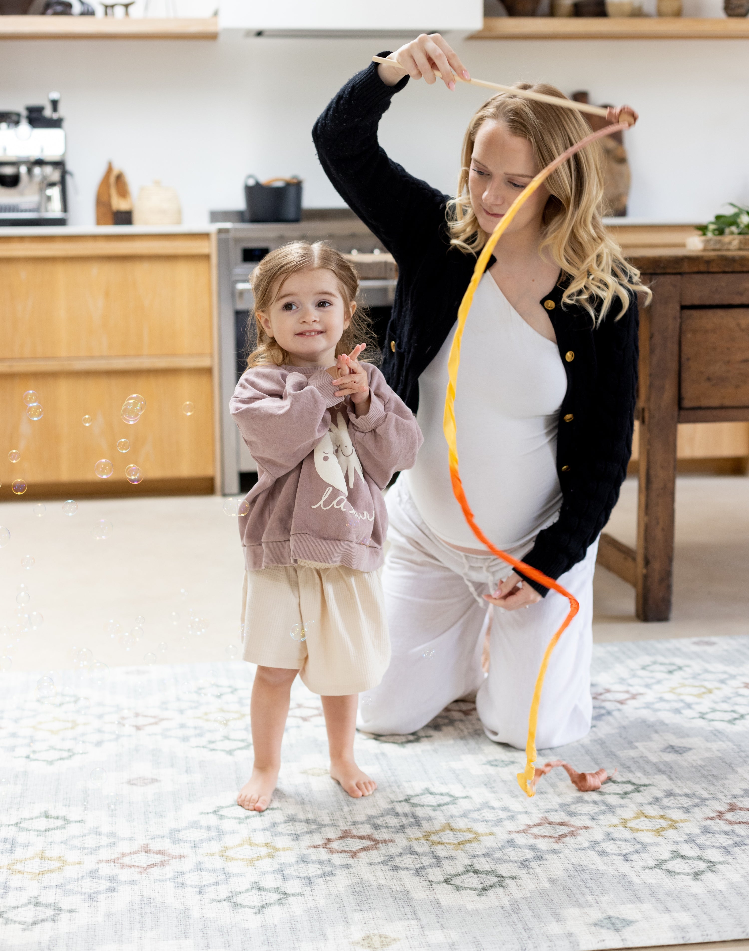 Woman and child playing in the kitchen on a geometric pattern play mat