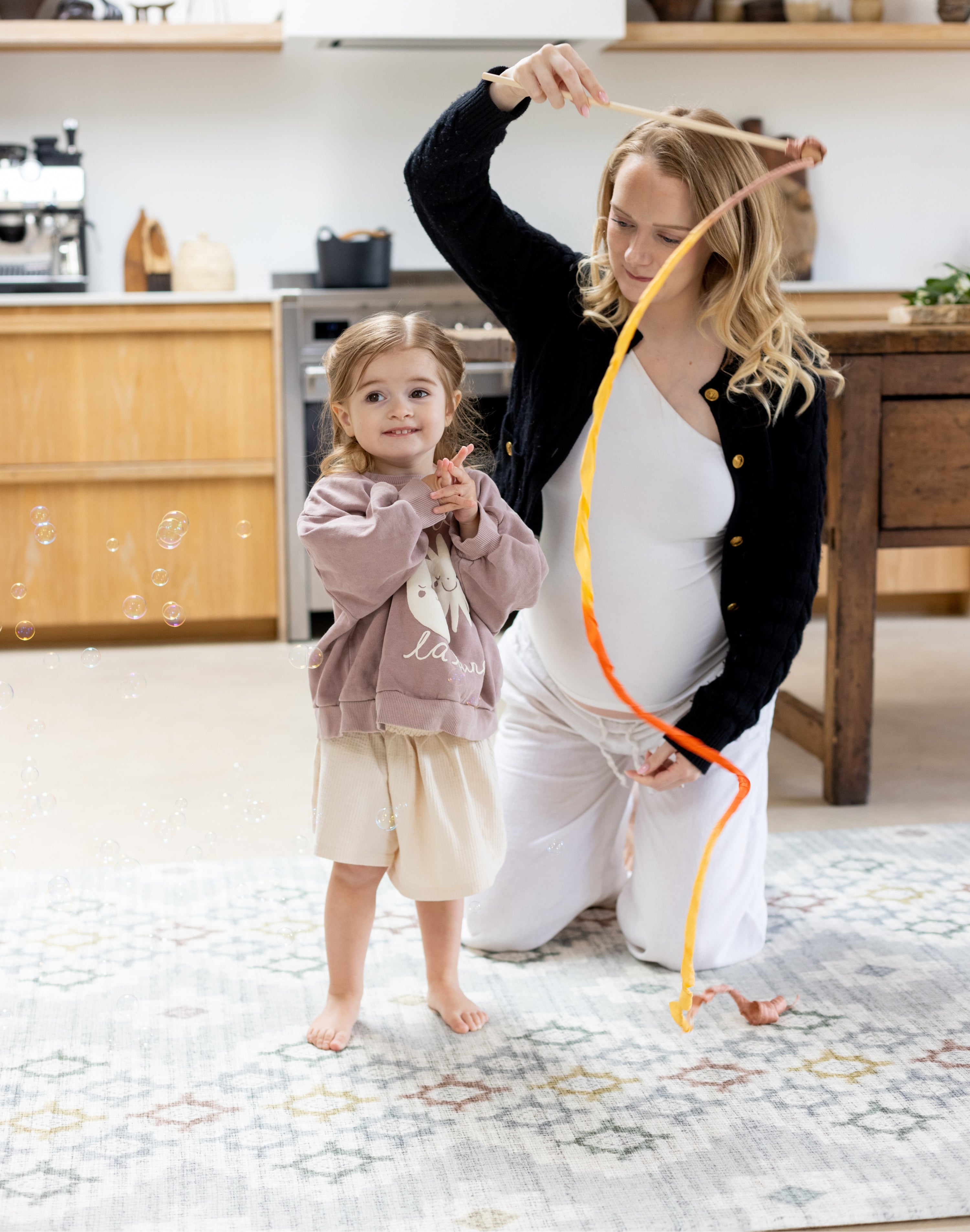 Woman and child playing in the kitchen on a geometric pattern play mat