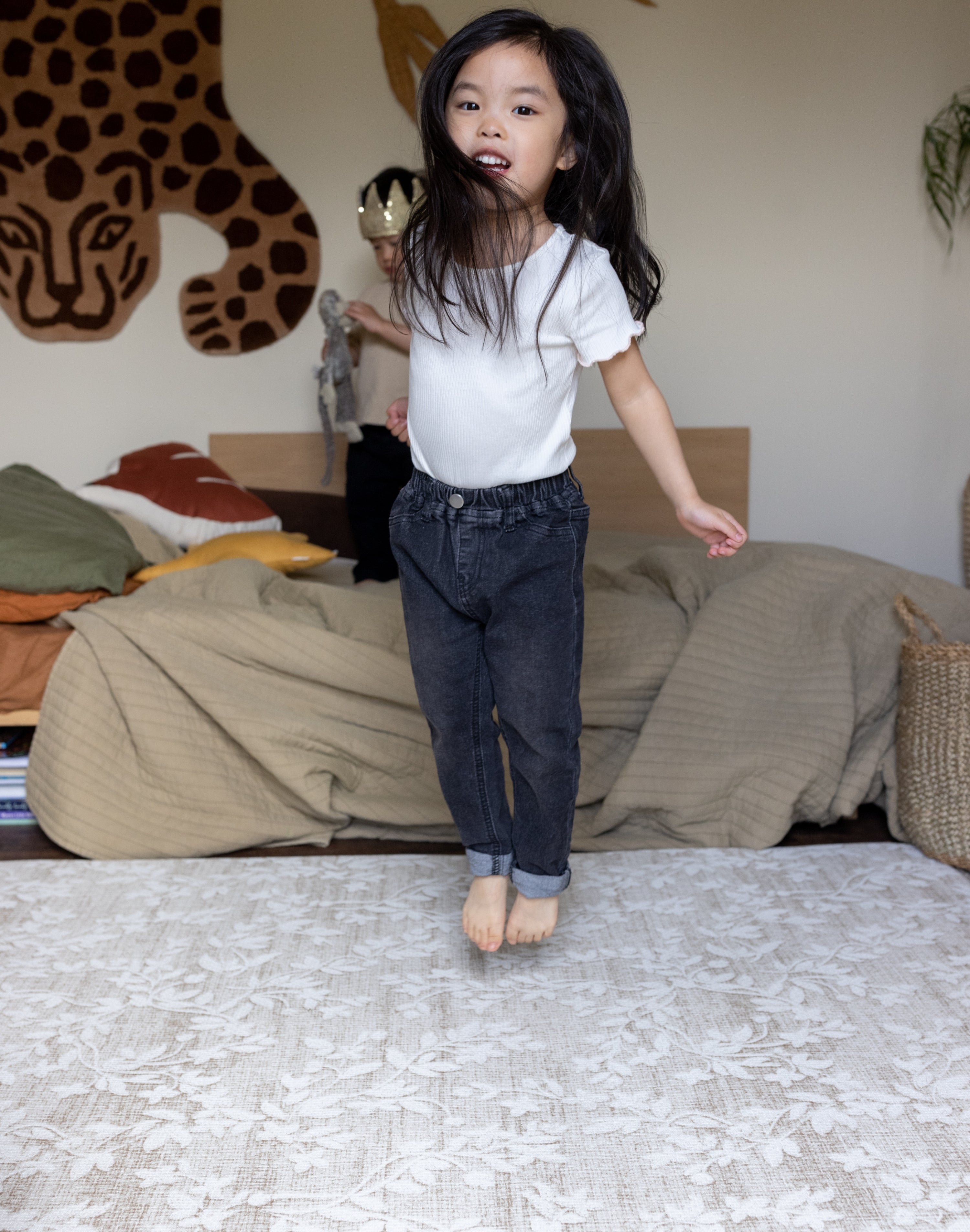 Child jumping on a thick memory foam floral play mat