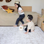 Two children playing on a large floral play mat from totter and tumble
