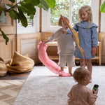 Three children playing on a floral rug-like play mat