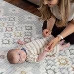 Woman interacting with a baby on a patterned baby safe comfortable play mat