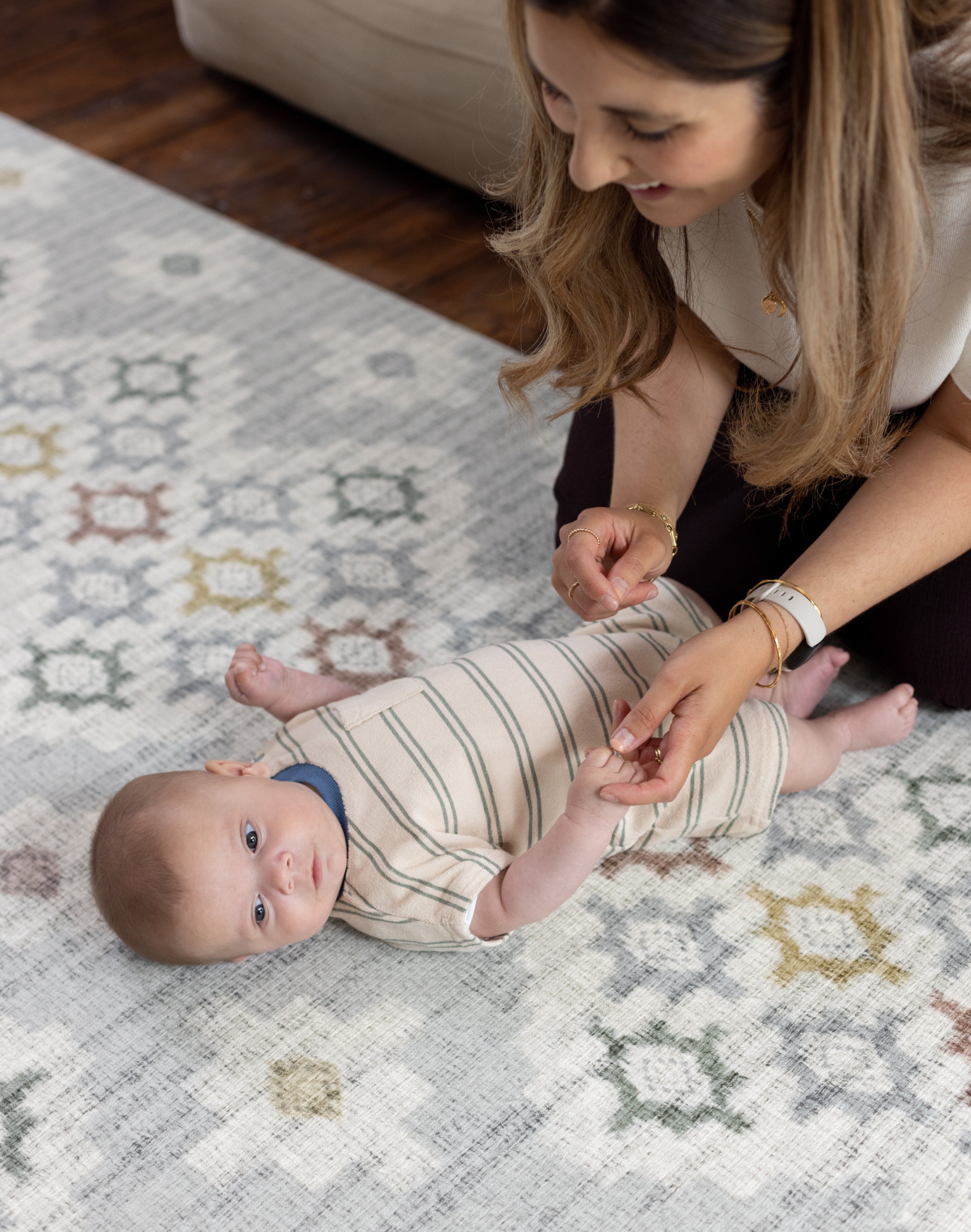 Woman interacting with a baby on a patterned baby safe comfortable play mat
