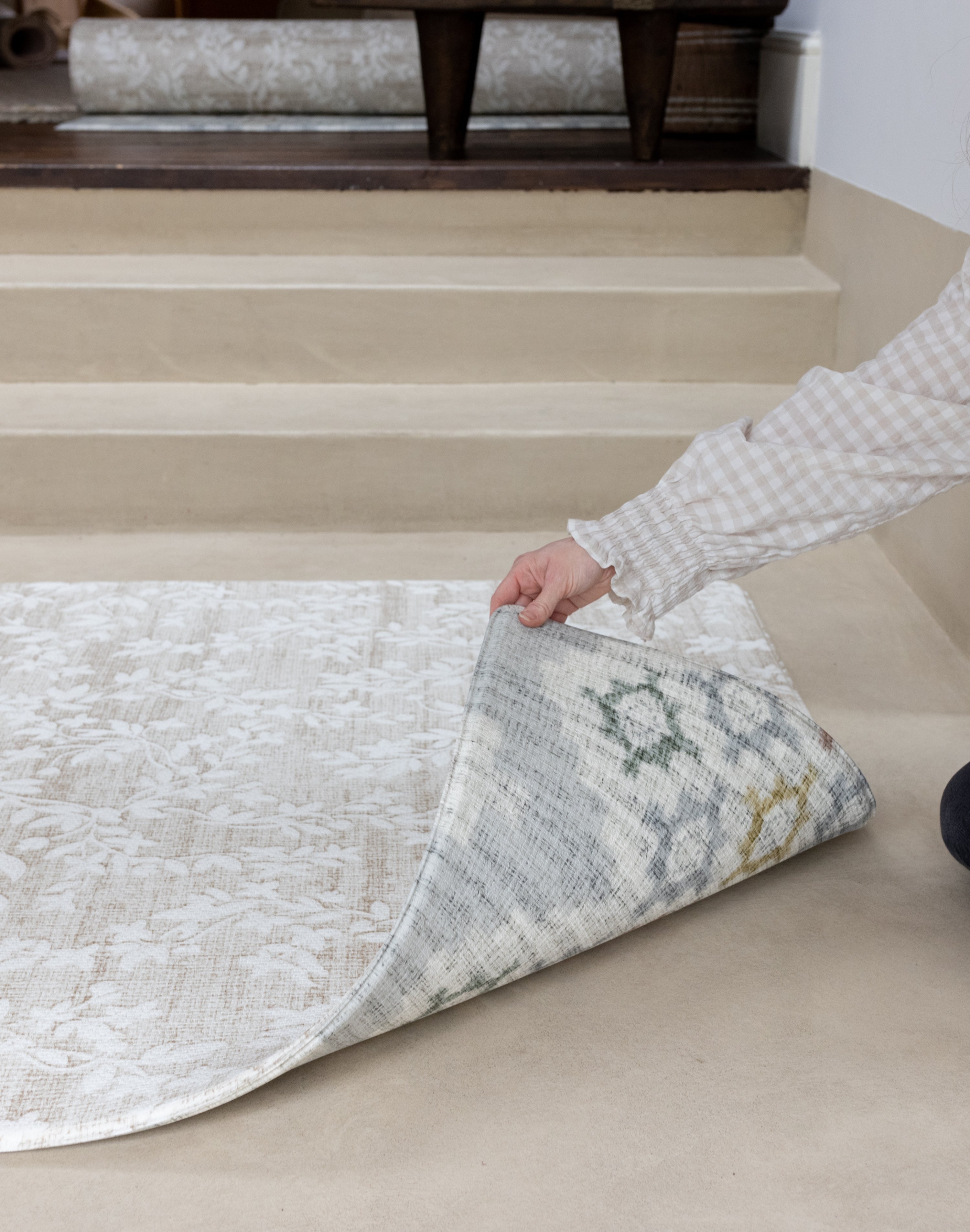 person showing two sides of a thick memory foam reversible play mat with floral and geometric designs