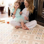 Woman and child sitting on a patterned rug-like comfortable play mat