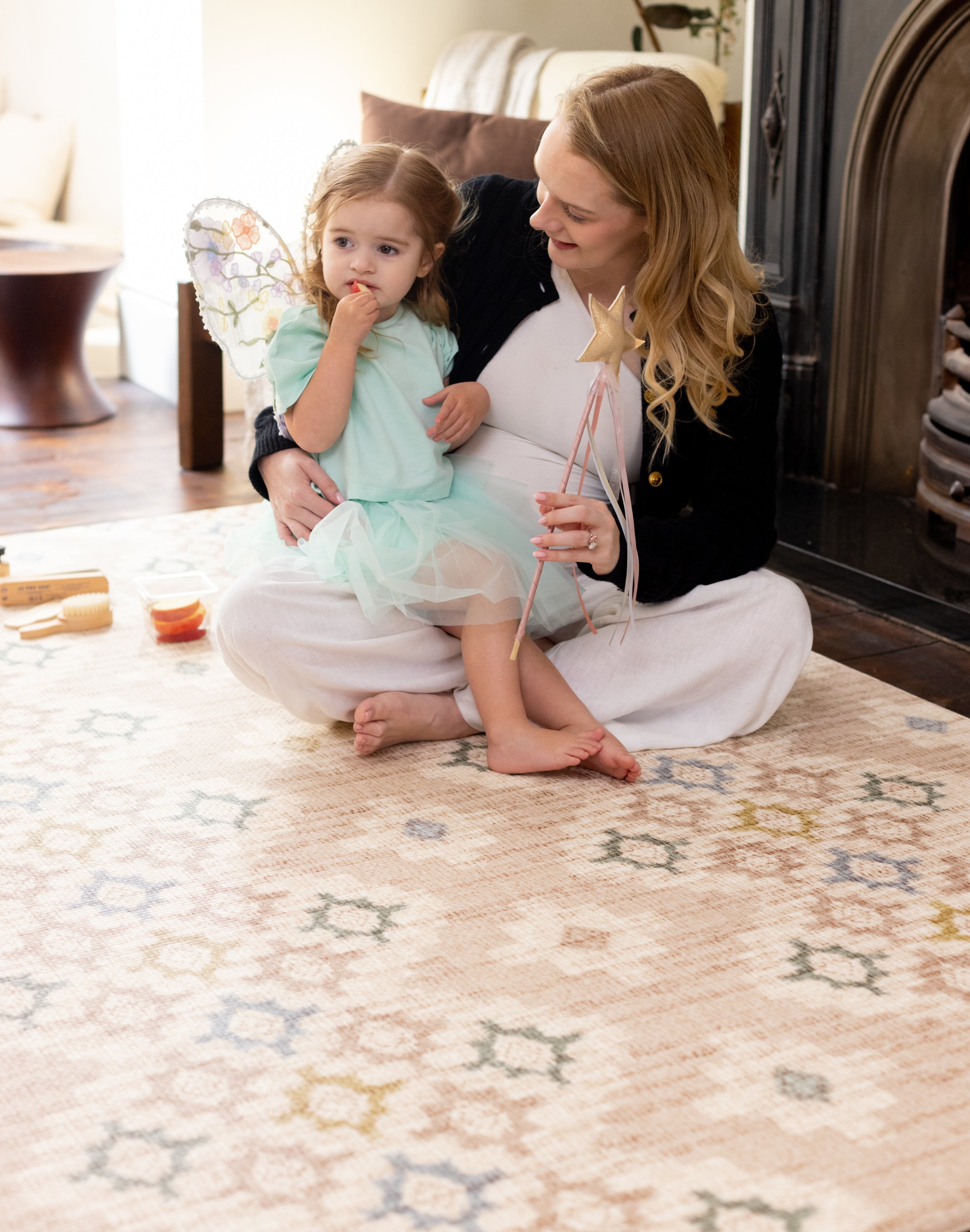 Woman and child sitting on a patterned rug-like comfortable play mat