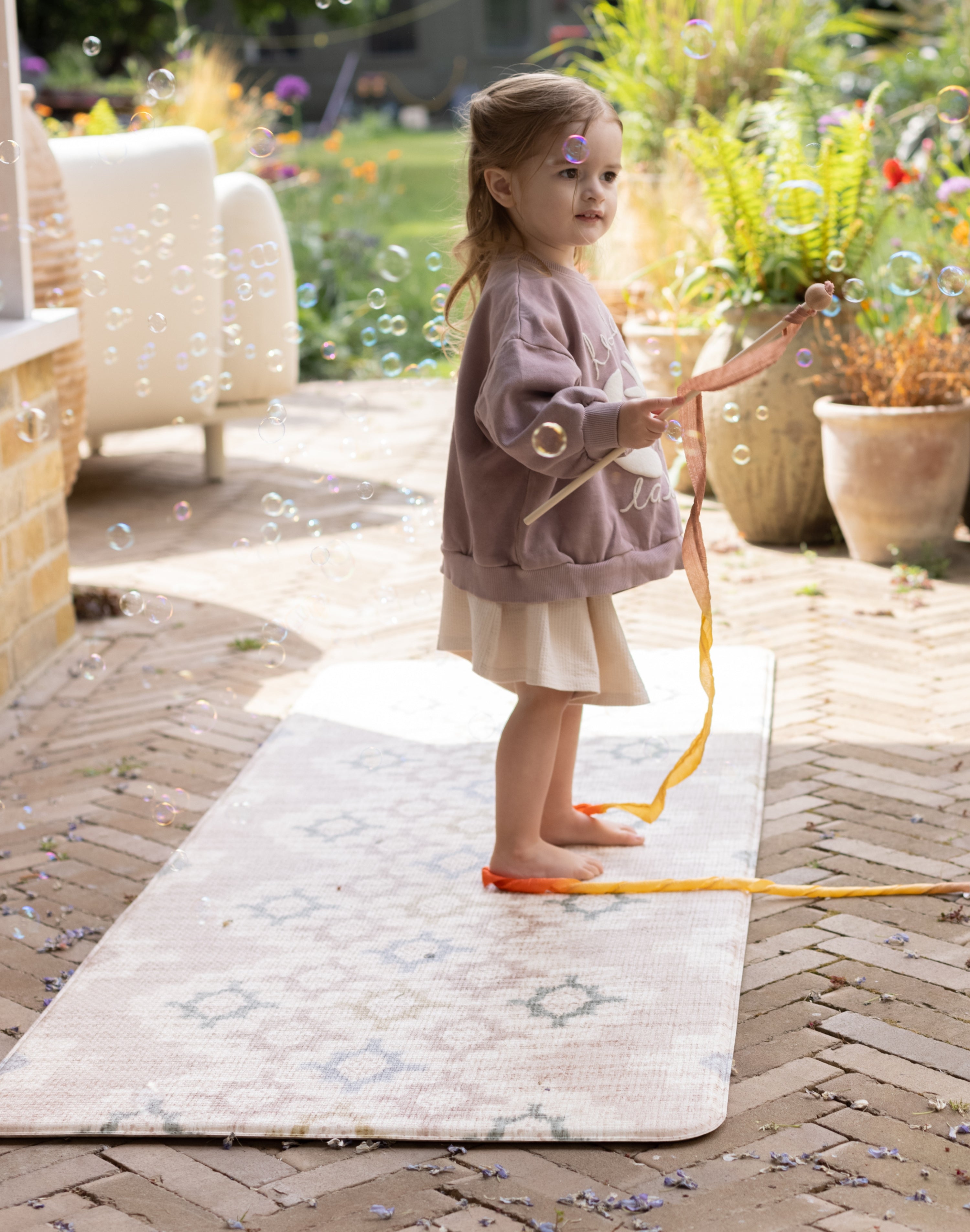 Child play outside on a comfortable easy to clean, wipeable totter and tumble play mat