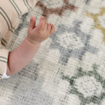Close-up of a baby's hand on a patterned totter and tumble play mat