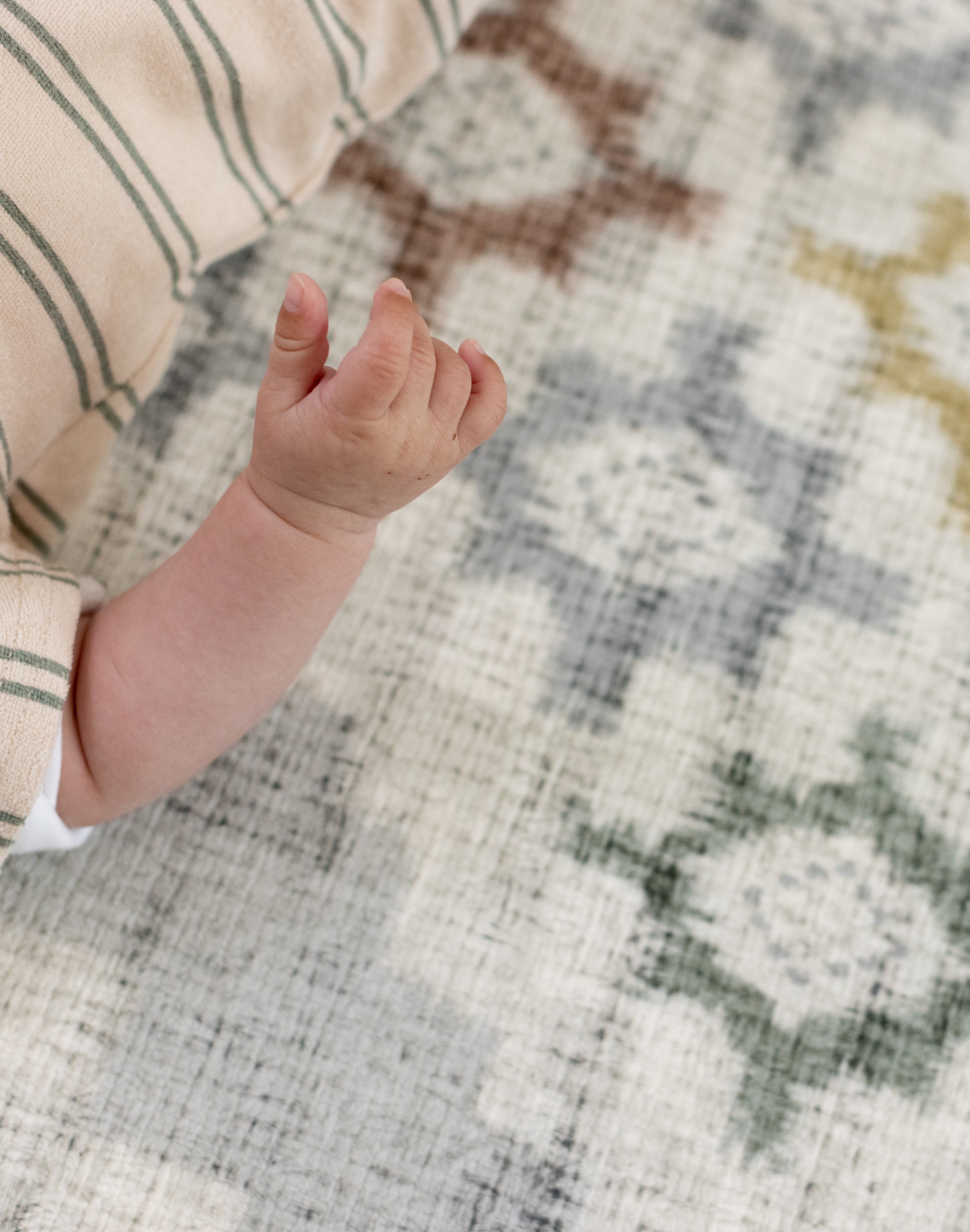 Close-up of a baby's hand on a patterned totter and tumble play mat