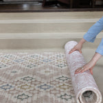 person rolling up a reversible patterned play mat with geometric and floral designs