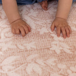 Close-up of a baby's hands on a patterned totter and tumble memory foam play mat