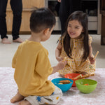 Two children sitting on a floral pink memory foam play mat laughing