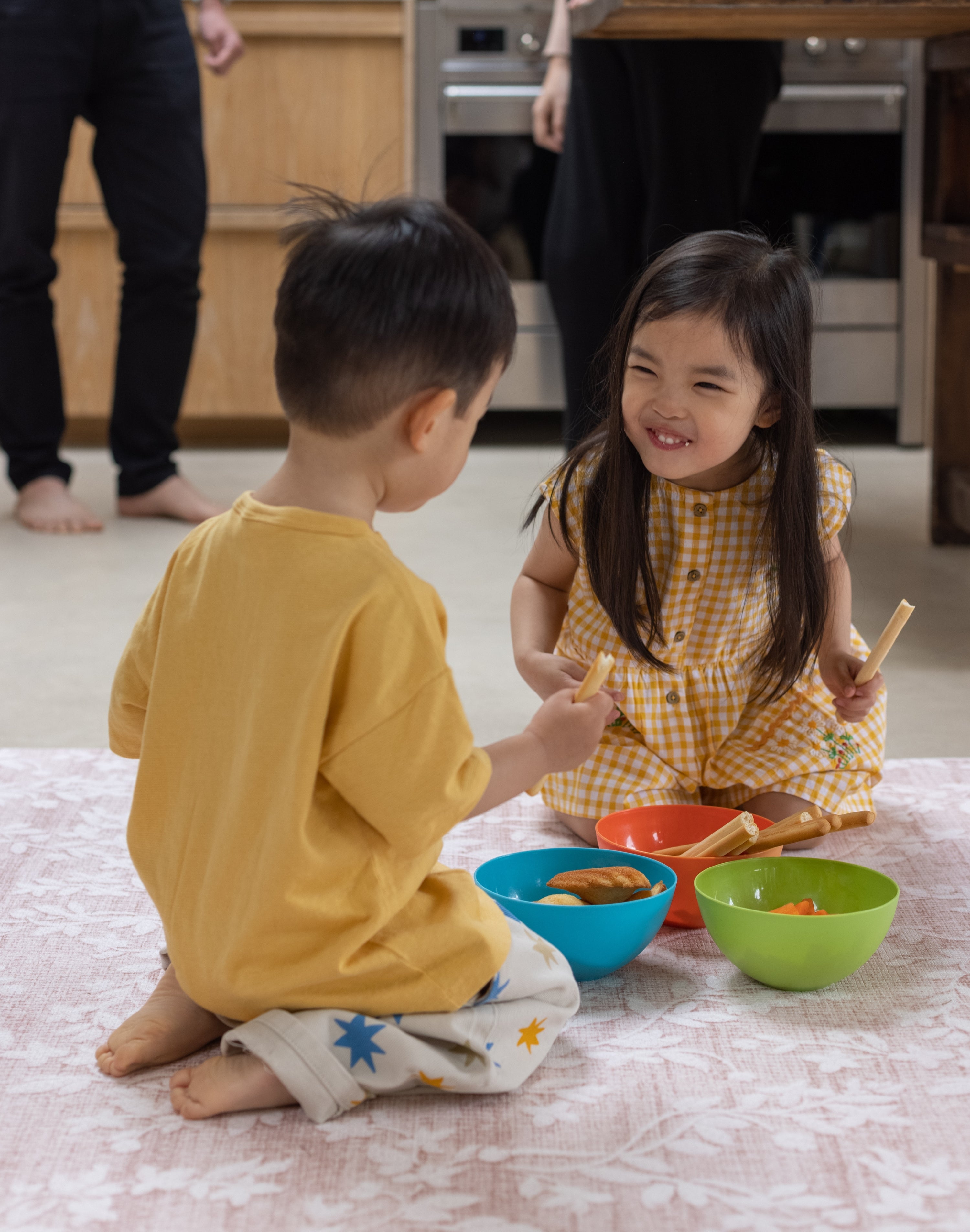 Two children sitting on a floral pink memory foam play mat laughing