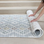 Person rolling a patterned reversible play mat