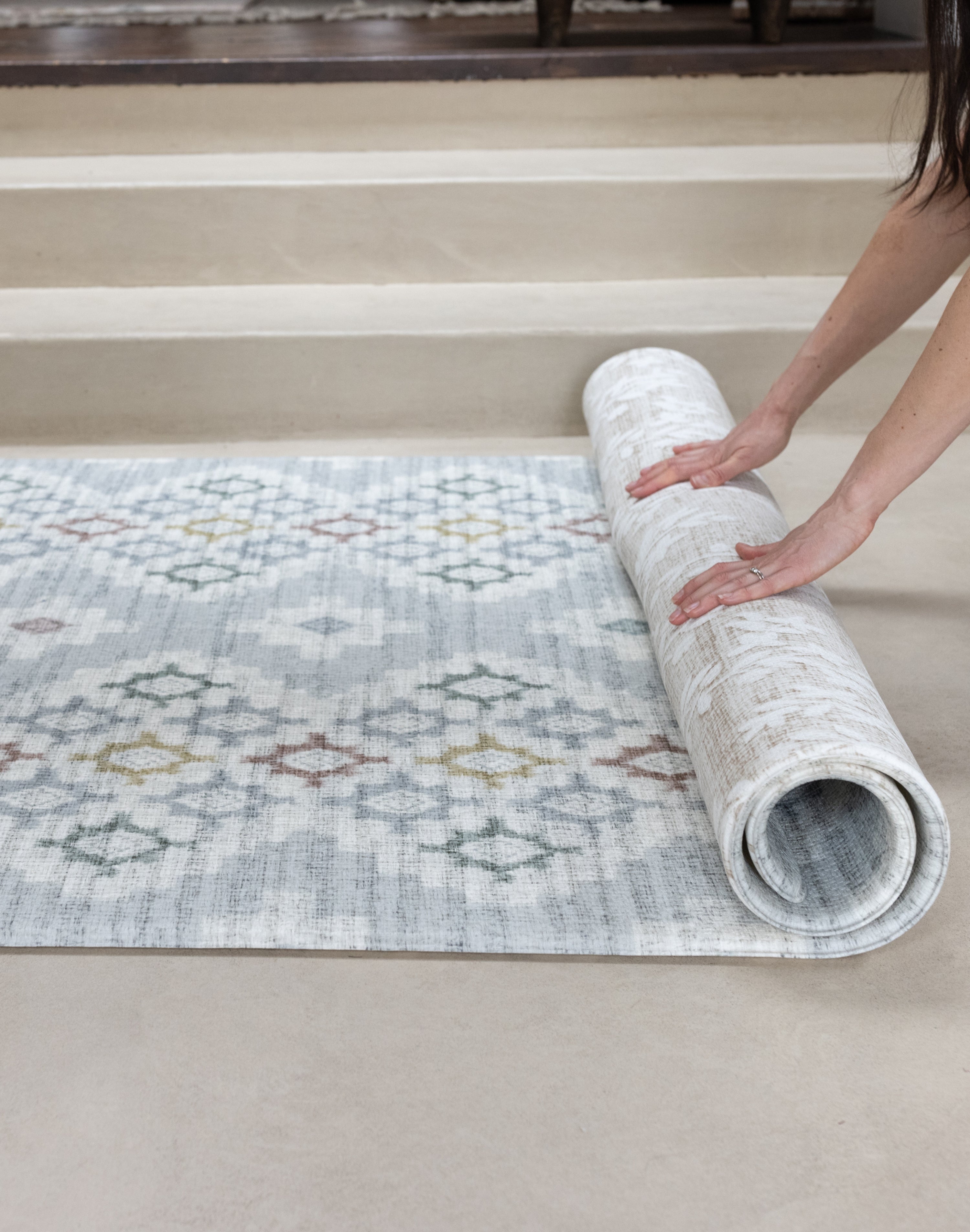 Person rolling a patterned reversible play mat