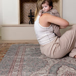 Parent cuddling baby while sitting comfortably on a Totter + Tumble Persian rug play mat.