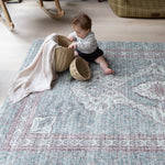 Baby playing with baskets on a patterned rug  playmat, surrounded by soft interiors