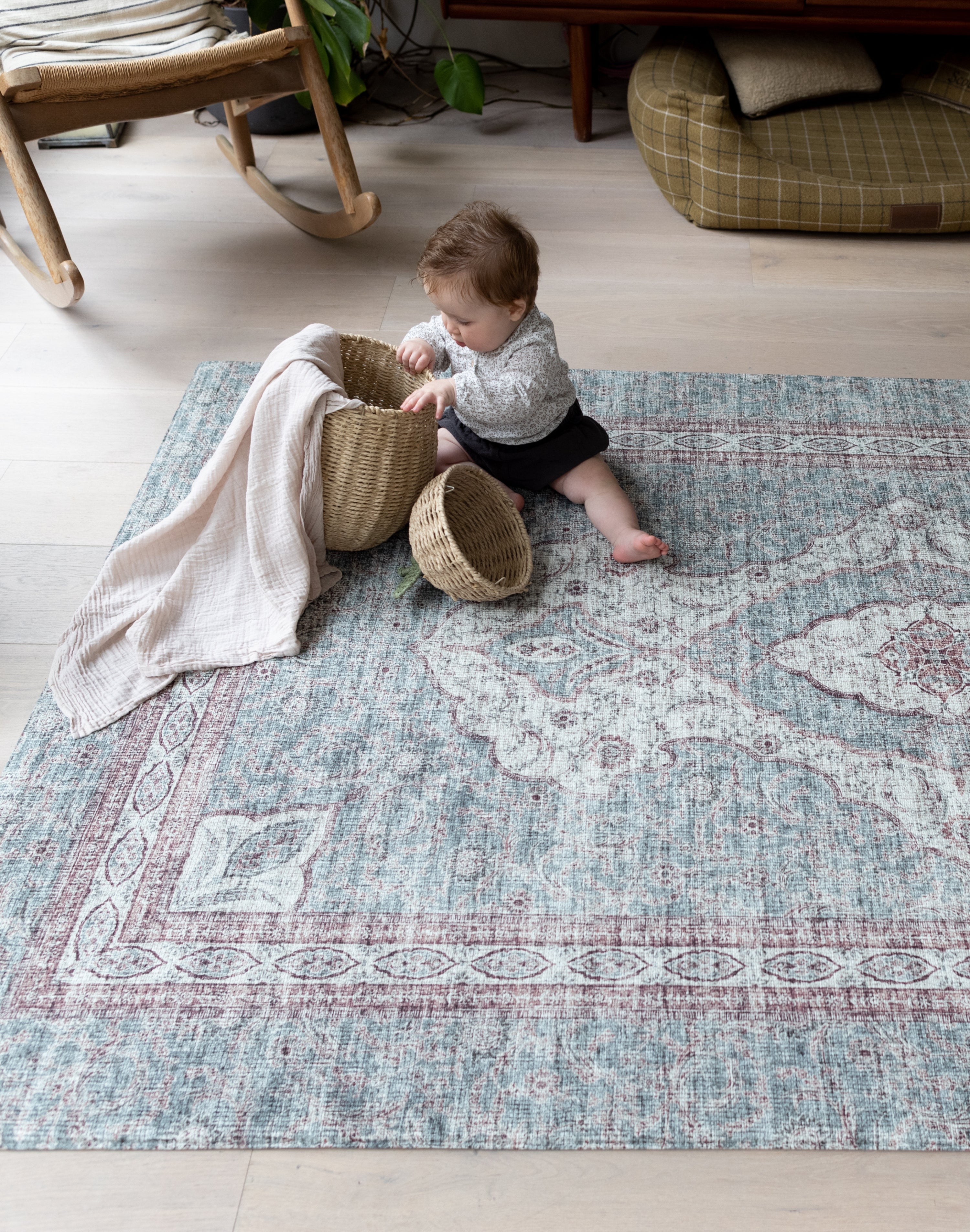 Baby playing with baskets on a patterned rug  playmat, surrounded by soft interiors