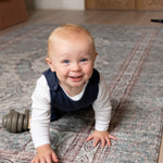 Smiling toddler crawling on Totter + Tumble play mat enjoying safe playtime.