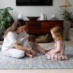 Family playtime on Totter + Tumble play rug in a bright modern living room.