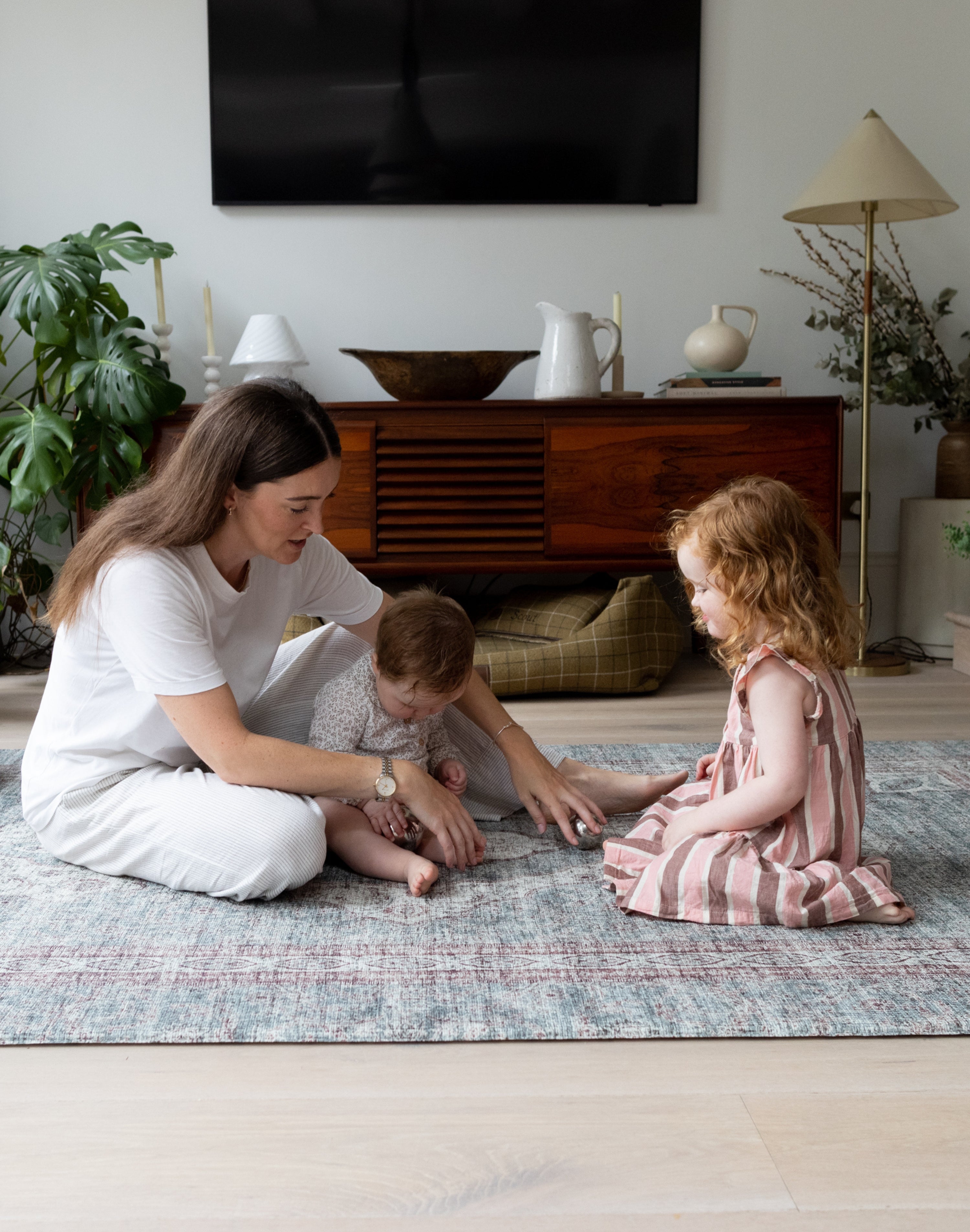 Family playtime on Totter + Tumble play rug in a bright modern living room.