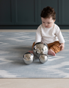 Baby sitting and playing with sensory toys on Light blue and beige play mat with subtle diamond design inspired by ikat motifs ideal for family living spaces