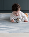 Baby laying on Childrens play mats the whole family will enjoy The Atlas has a striking Ikat design that looks like a rug in the home available in four sizes so you can unroll just where you need it