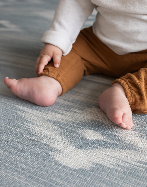 Close up of surface and babies feet on Padded baby play mat that the whole family will love The Atlas is available in four sizes so you can choose the perfect size for your family space