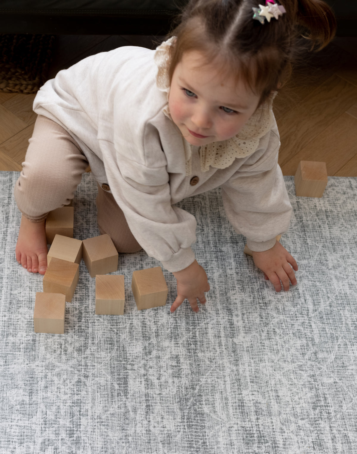Child playing with wooden blocks on a Persian style rug-like play playmat from Totter and Tumble