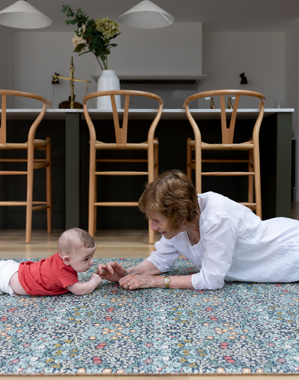 blackthorn morris & co collaboration with totter and tumble granny playing with grandchild tummy time in kitchen looks like an area rug but padded playmat sealed surface and easy to clean