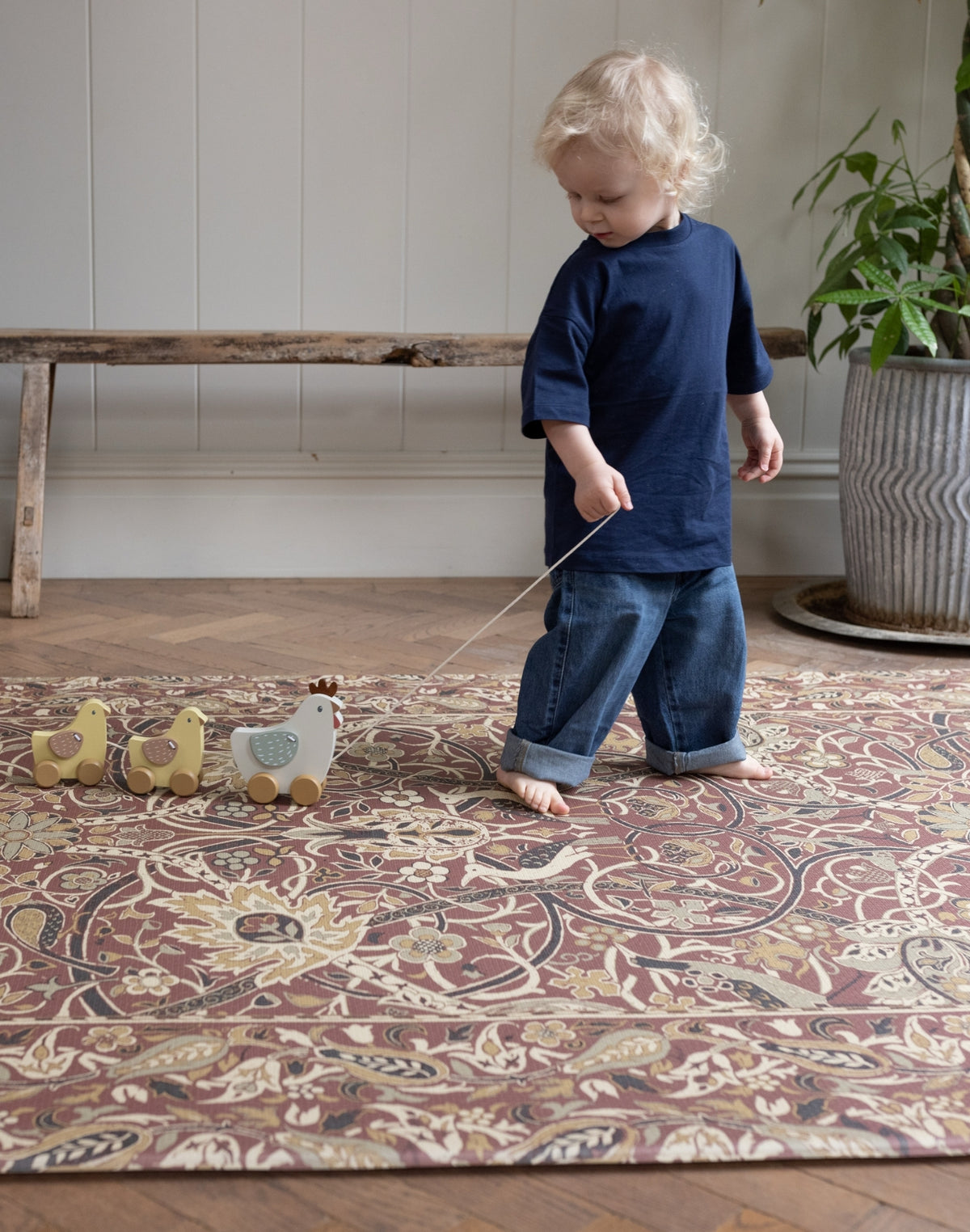 Child pulling a toy along the Bullerswood madder gold playmat from totter and tumble | SKU: WM BULLERS/WB MADDER GOLD STD,WM BULLERS/WB MADDER GOLD COMP