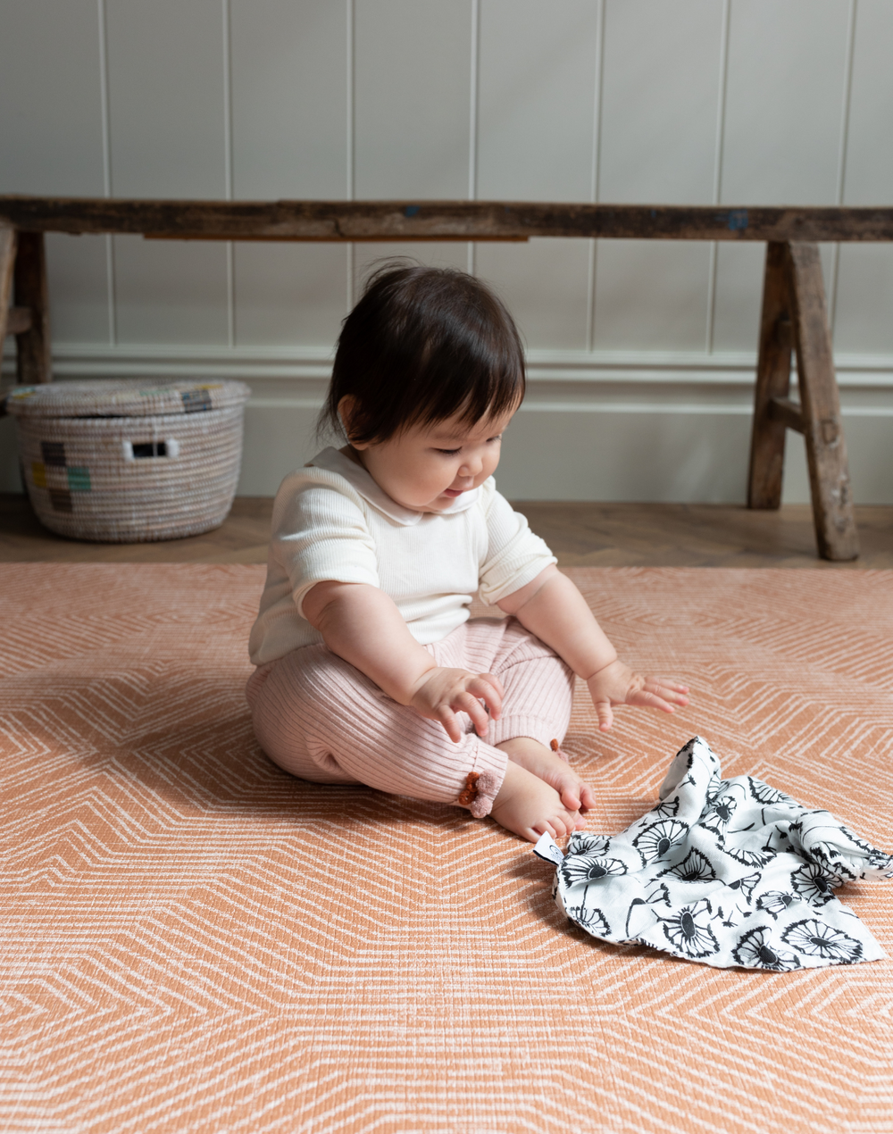 baby girl plays on kids play mat with a stylish orange design