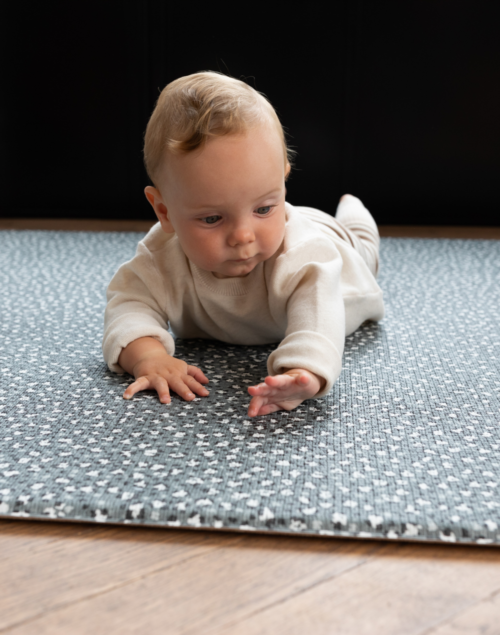 Baby lays on tummy on supportive play rug with leopard print design