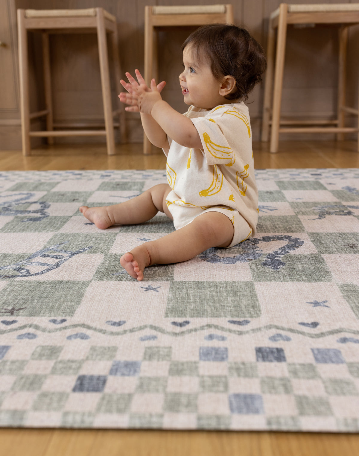 Baby sitting on the checker, a soft cushioned memory foam play mat from totter and tumble