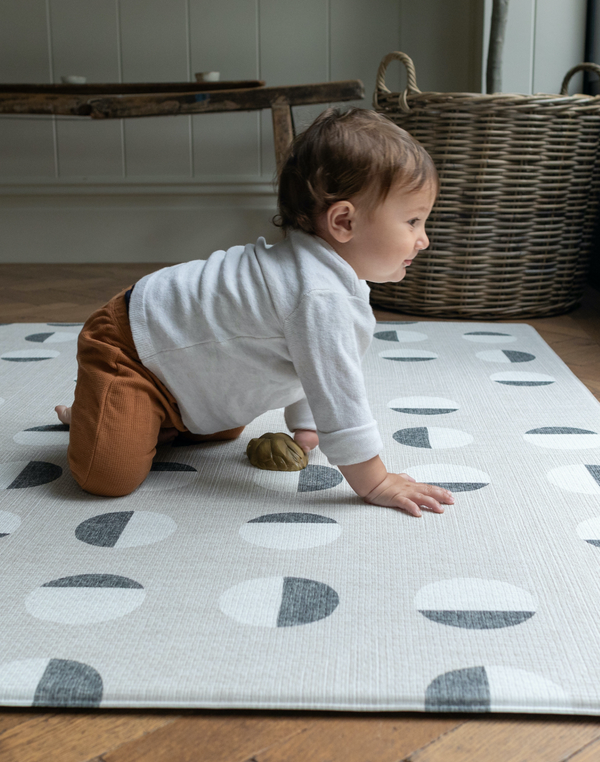 child enjoys playing on foam play rug created with an organic polka dot motif for a modern decor look in the family home.
