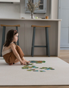 Little girl sits on an ergo foam floor mat putting together a puzzle enjoying comfort from the memory foam
