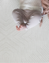 A baby lays on the neutral Globe Trotter play rug that offers great support with thick memory foam for ultimate comfort