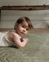 Baby enjoys sensory floor play on one piece memory foam play rug in a modern olive colorway