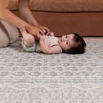 Baby lying on soft gray Totter & Tumble large play mat in stylish living room