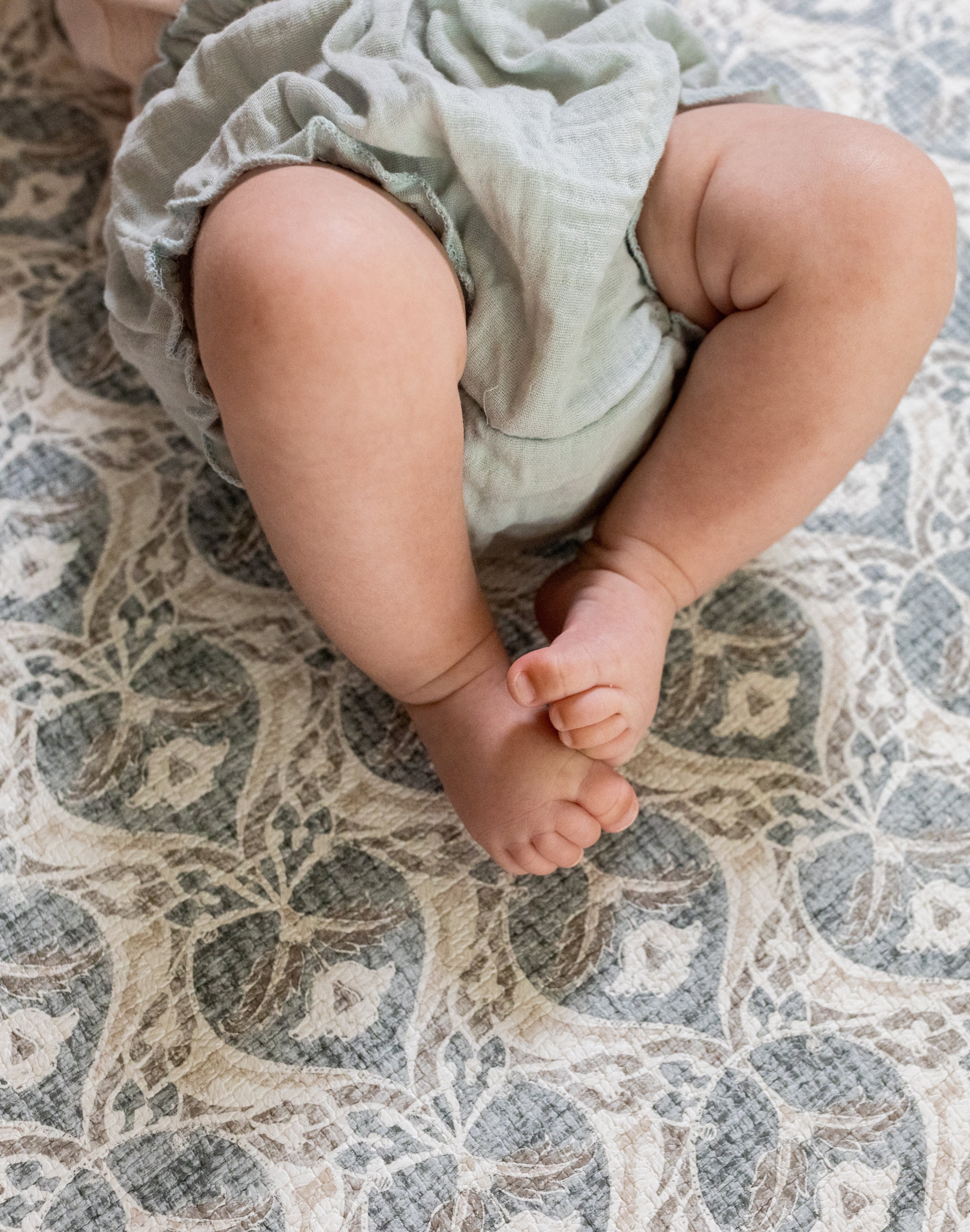Baby's feet  lying on a soft grey textured play mat