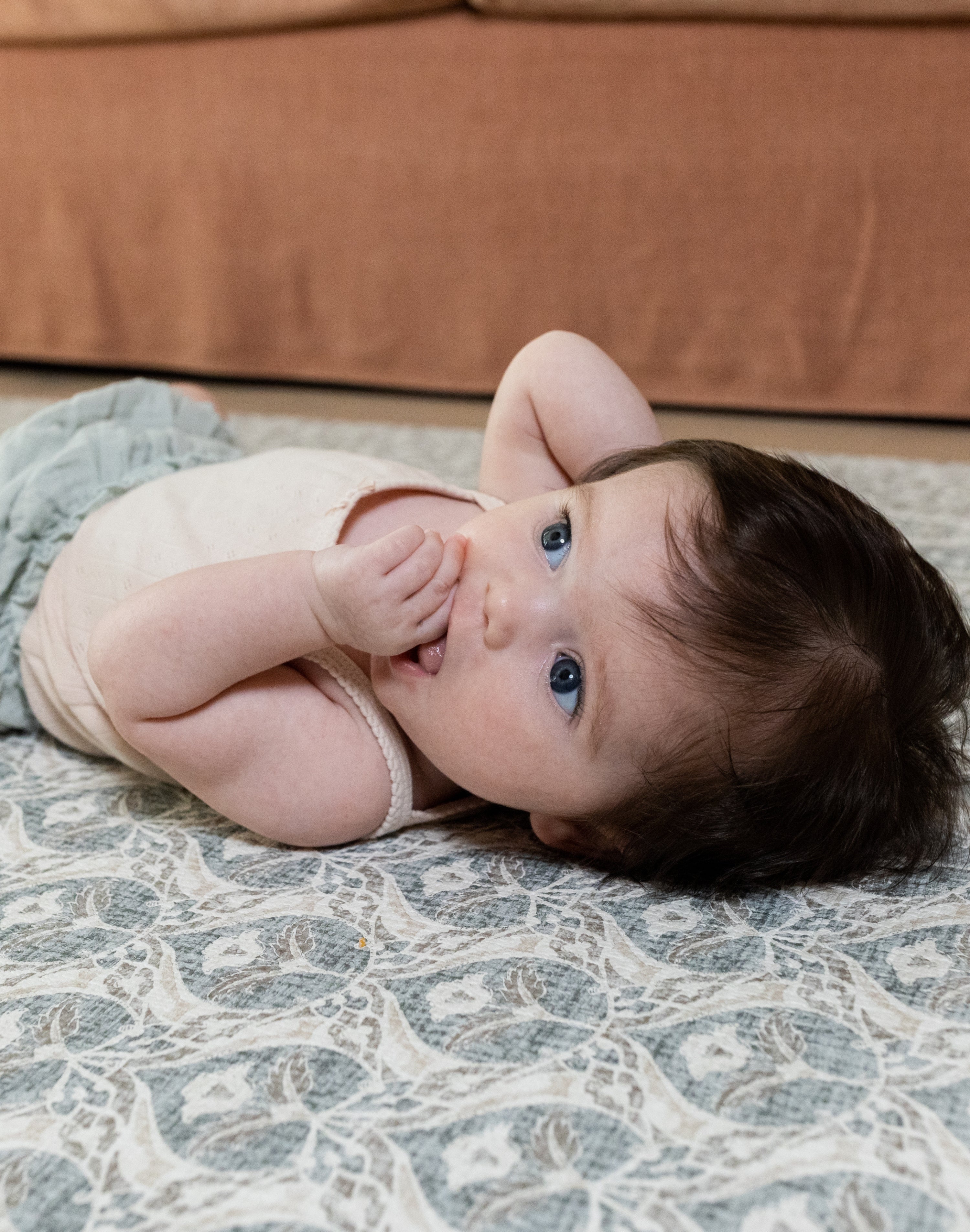 Baby relaxing on soft grey baby mat in chic family room