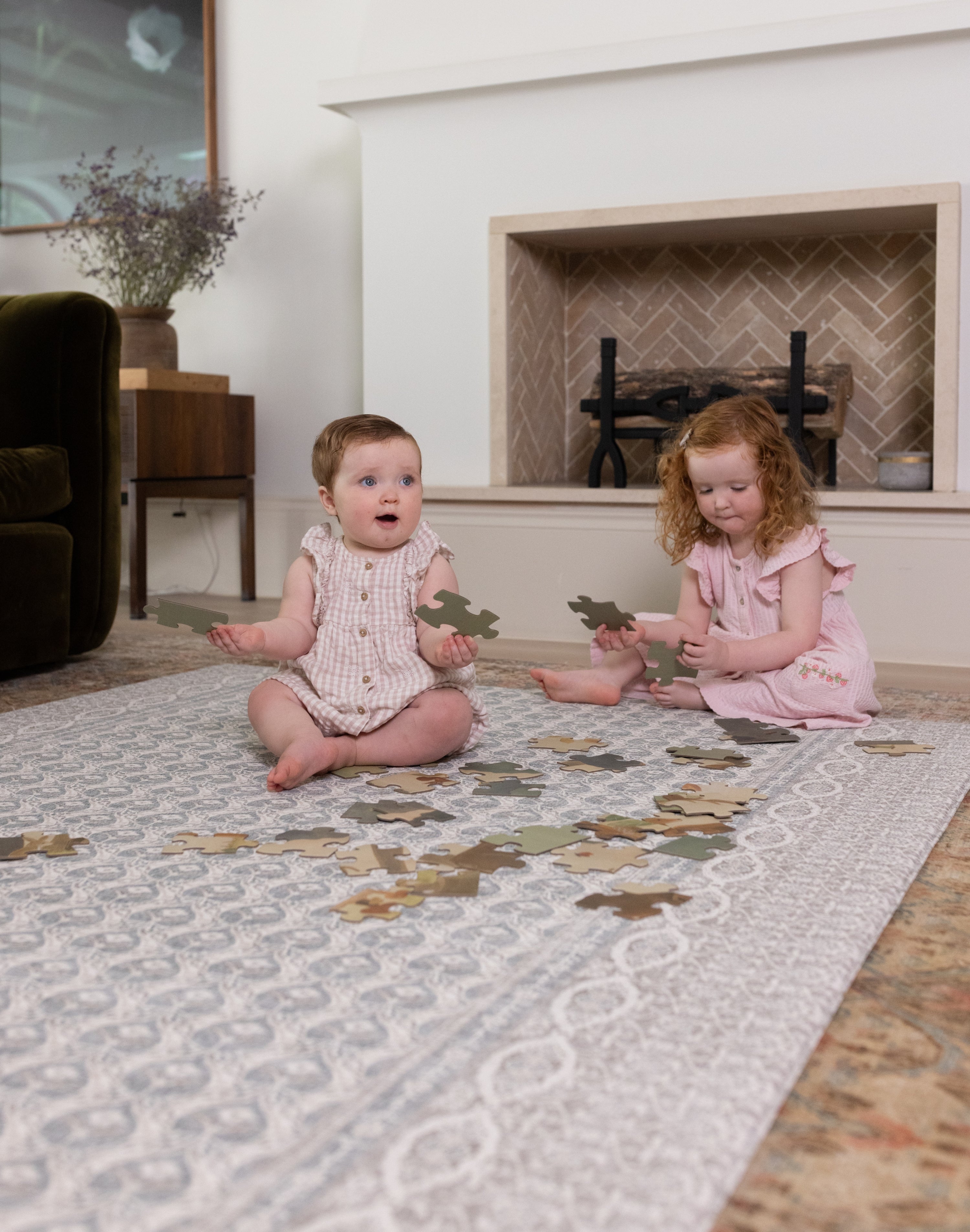 Two young children playing on an elegant Totter + Tumble play mat in a living room