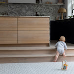 Toddler walking across large soft baby mat in neutral living space