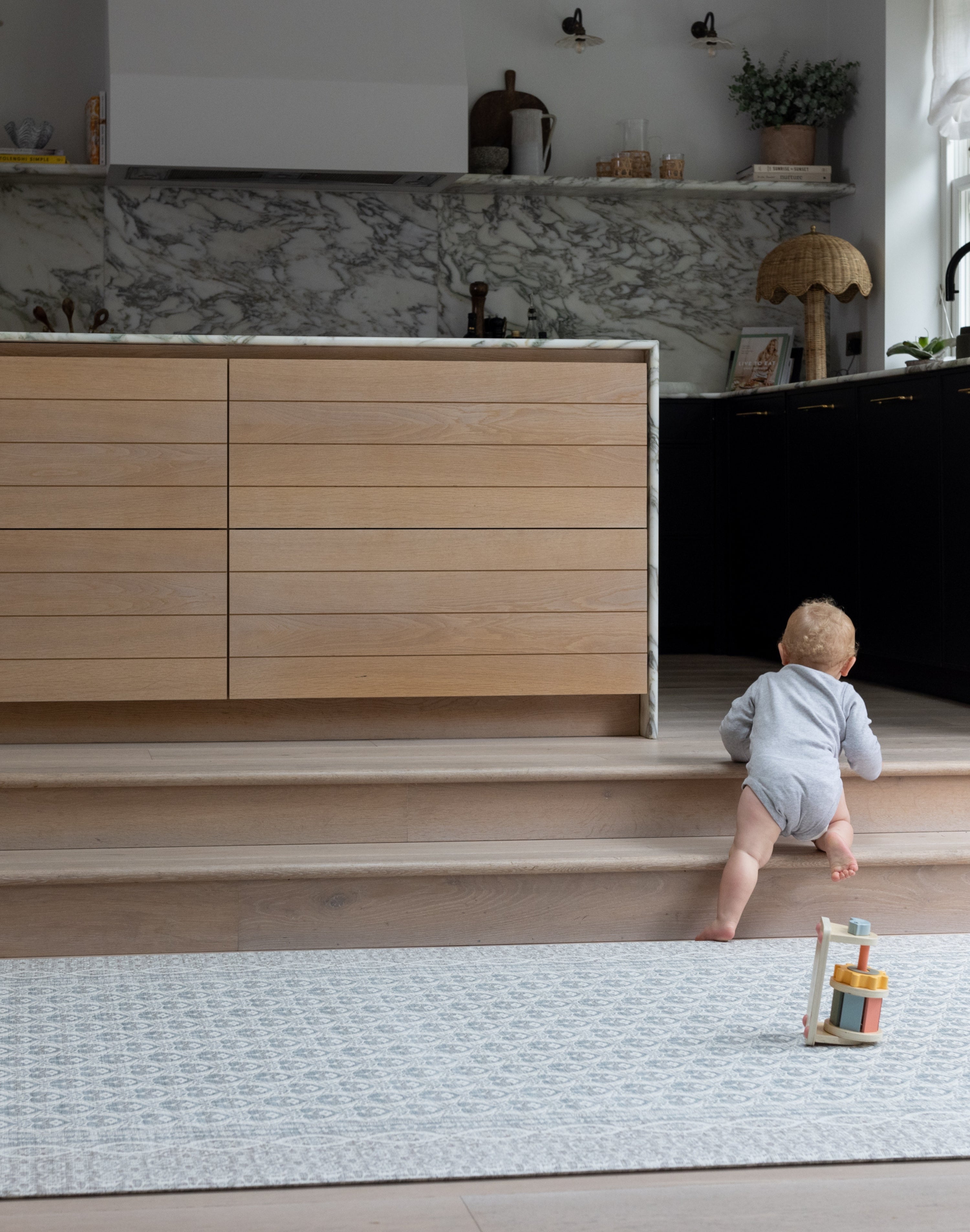 Toddler walking across large soft baby mat in neutral living space