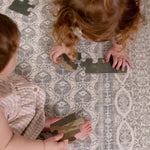 Two toddlers playing with toys on washable large baby mat in soft colors