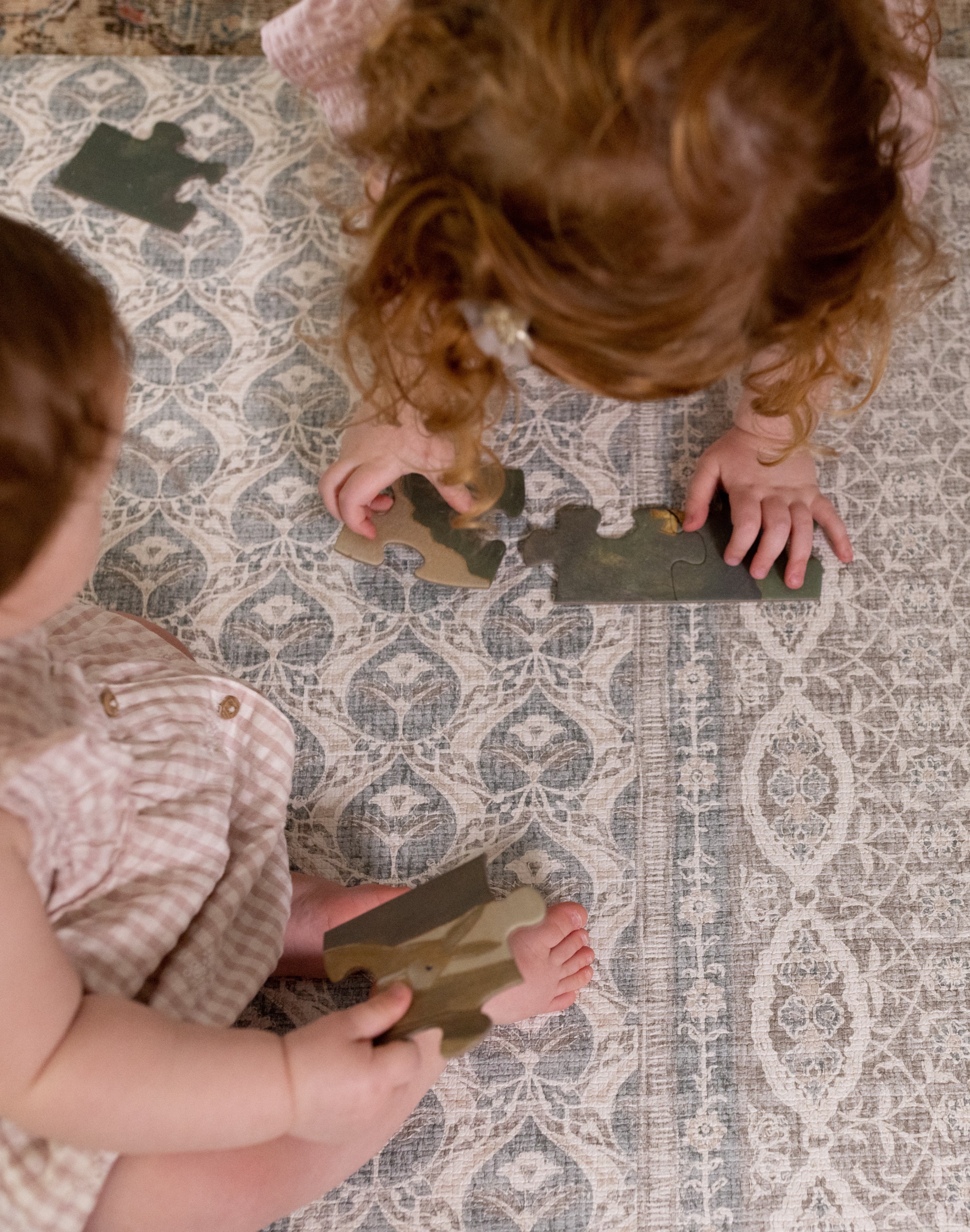 Two toddlers playing with toys on washable large baby mat in soft colors