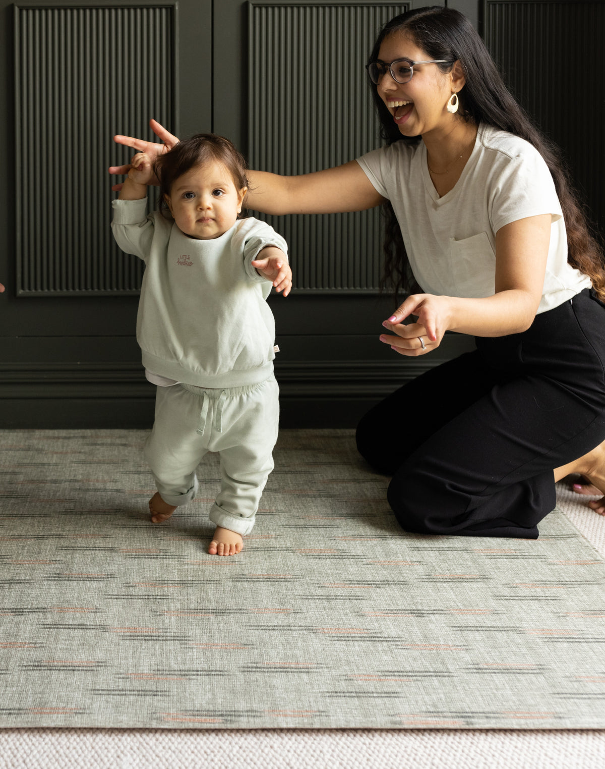 Woman encouraging a baby to walk on a super soft thick memory foam totter and tumble play mat