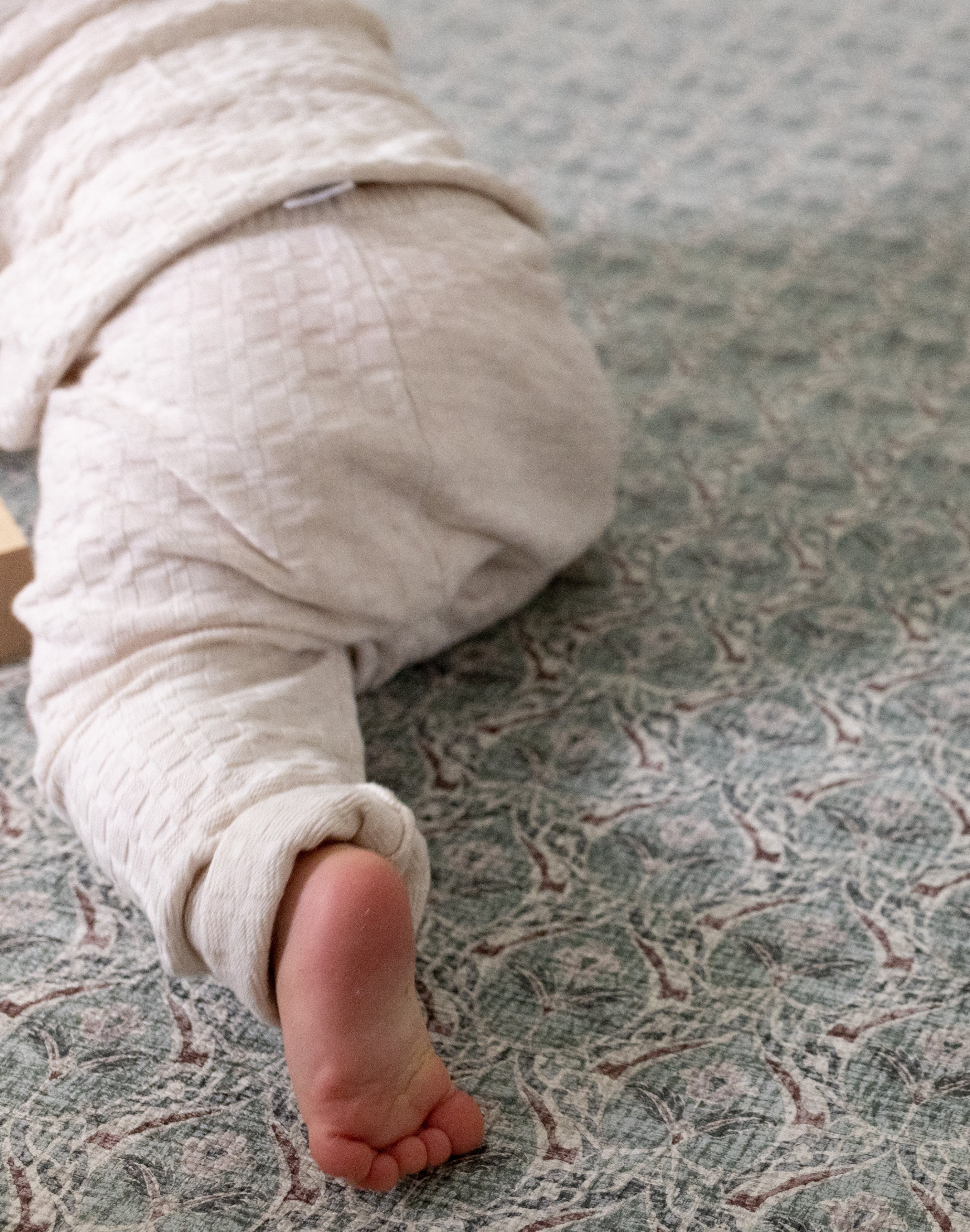 Crawling baby on a thick memory foam play mat from Totter + Tumble